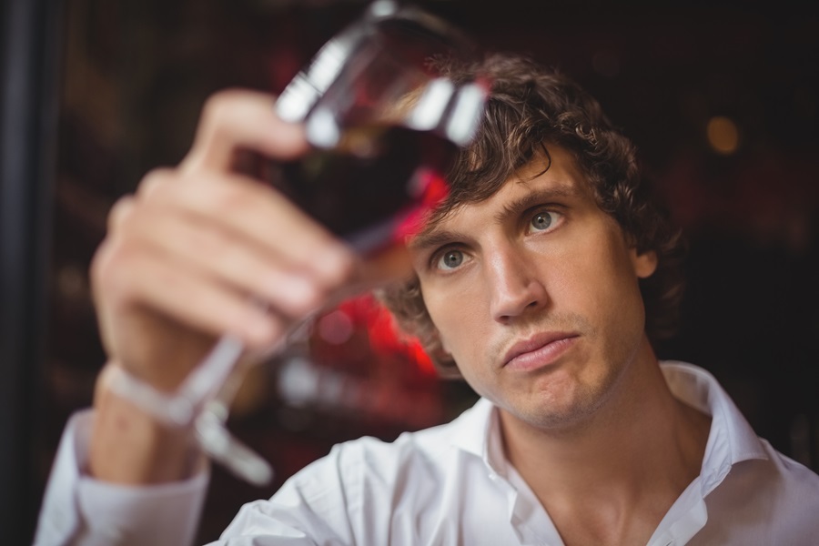 uomo -che guarda-un-bicchiere-di-vino-rosso per la degustazione
